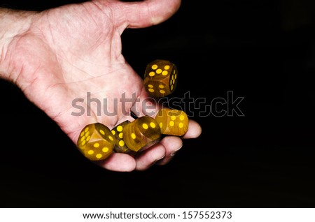 Hand throwing wooden dices, on black