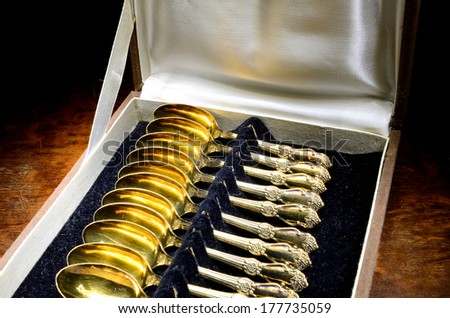 Box of vintage gold-plated teaspoons on mahogany table