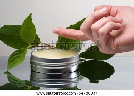 Container with salve and dab of salve on tip of female finger