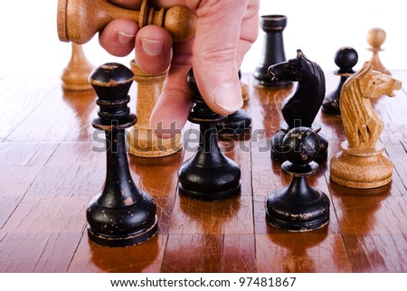 Bishop in hand over a chess board. Wooden chess set