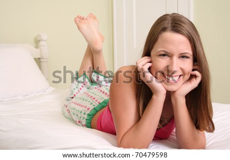 Happy young woman on bed in pajamas