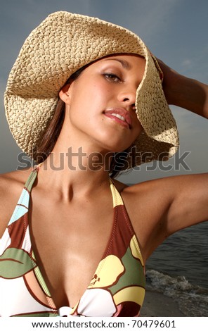 Pretty portrait of young latina with floppy hat at the beach