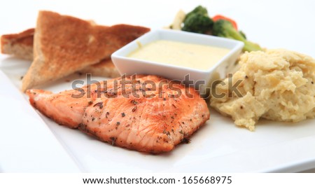 Salmon steak in white dish with vegetables