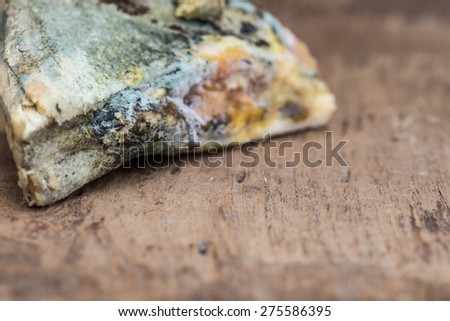 Mouldy bread on cutting board, on wooden background