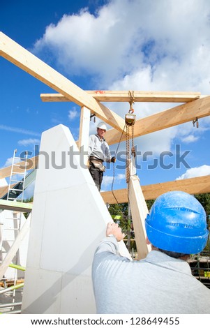construction workers at work with wooden  roof construction of a new home