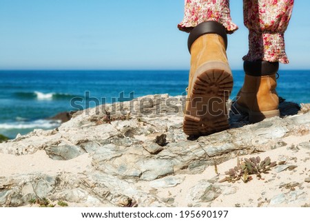 Closeup Hiking boots  on mountain rocks with sea in background. Focus on sole