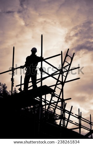 silhouette of construction worker with ladder on scaffolding. Purple toned