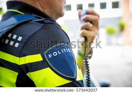 Dutch police officer, with portable or radio. Focus on badge with logo