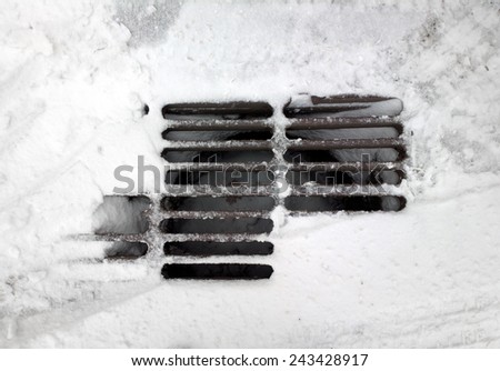 Storm drain covered by snow.