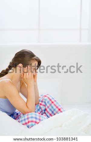 Girl with head ache sitting on bed