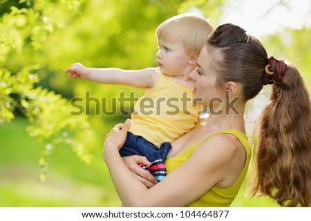 Outdoors portrait of mother and baby girl pointing in corner