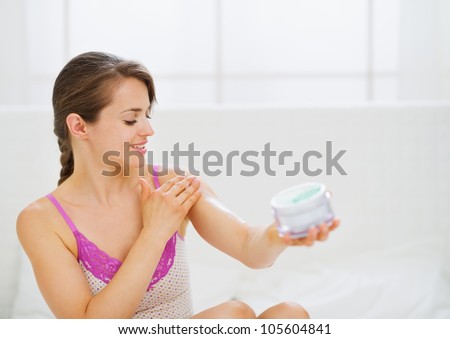 Portrait of self caring woman applying creme on arm