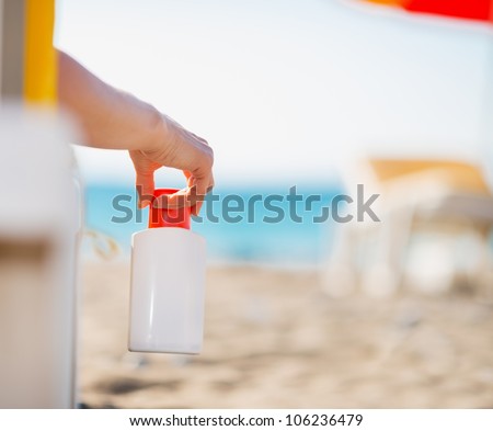 Closeup on bottle of sun block creme in female hand