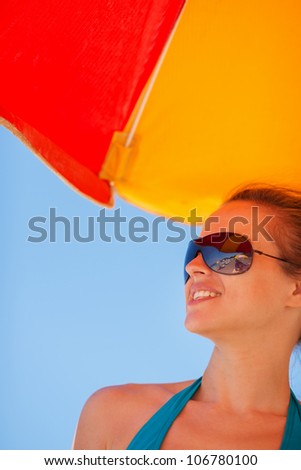 Happy woman in sunglasses on beach looking on copy space