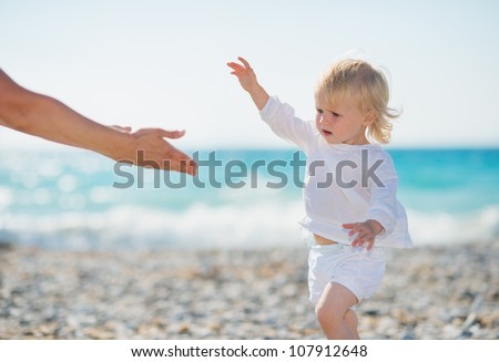 Baby walking to mothers outstretched hands