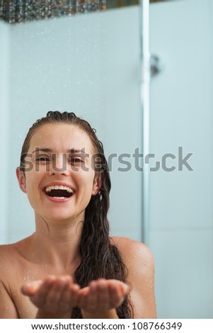 Happy woman catching water drops in shower under water jet