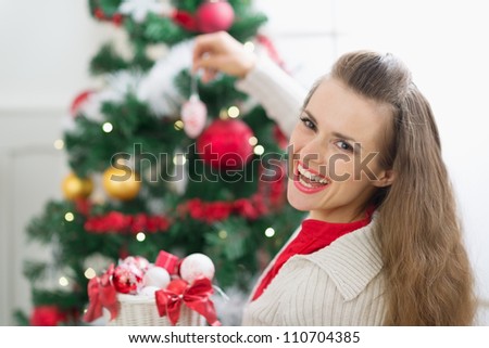 Happy young woman decorating Christmas tree