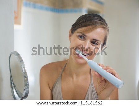 Young woman brushing teeth with electric toothbrush