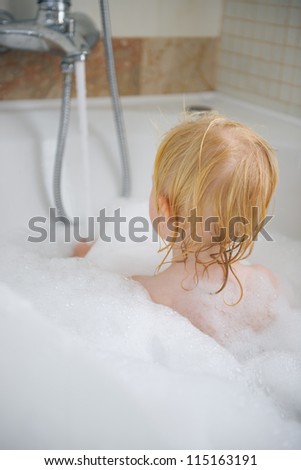 Baby in bath foam. Rear view
