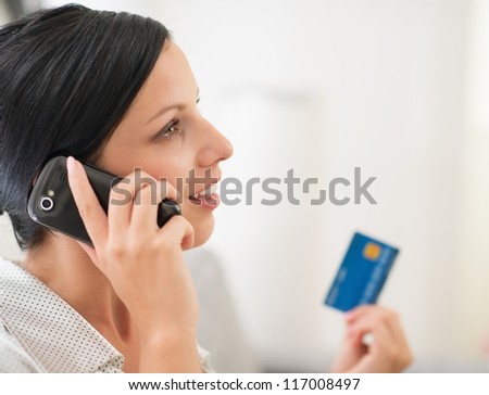 Young woman with credit card and speaking mobile phone