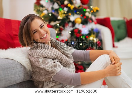 Happy Woman sitting near Christmas tree