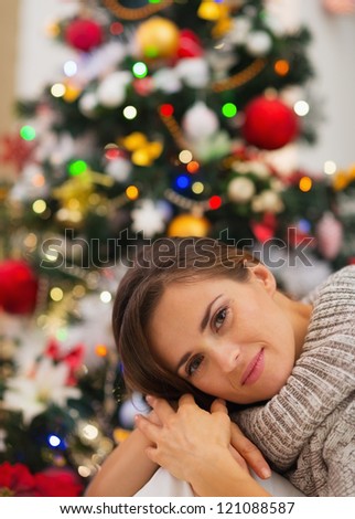 Portrait of dreaming young woman near Christmas tree