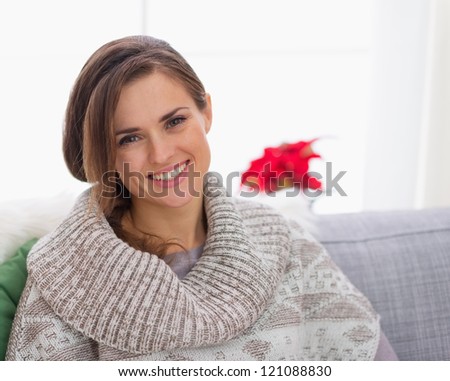 Portrait of smiling woman in knit sweater sitting on couch