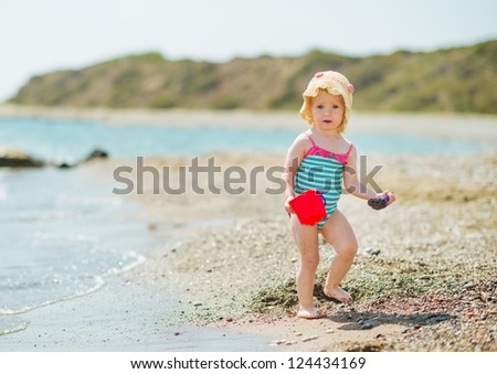 Baby playing with pail on sea shore