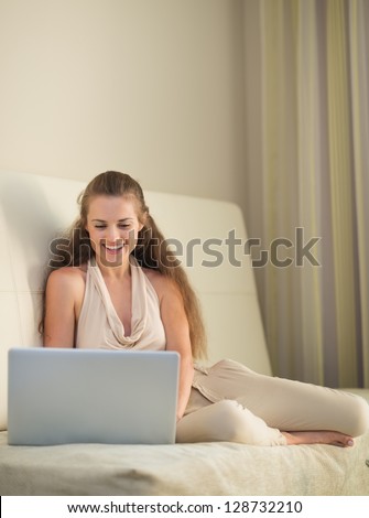 Smiling young woman on couch with laptop
