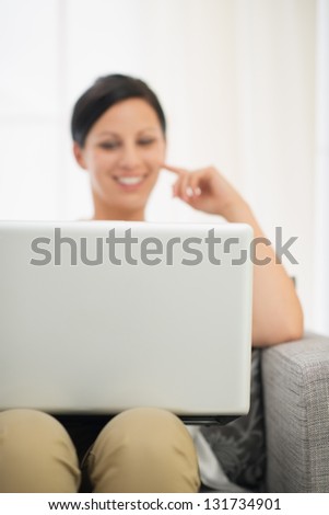 Closeup on laptop and happy young woman in background
