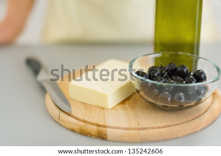 Closeup on knife cheese, olives and olive oil on cutting board