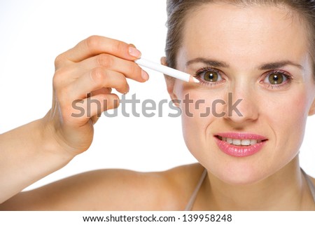 Beauty portrait of young woman applying white eye liner