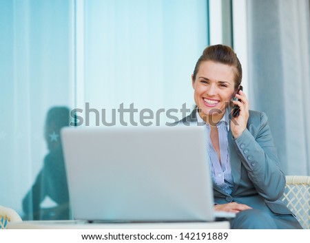 Happy business woman talking mobile phone on terrace