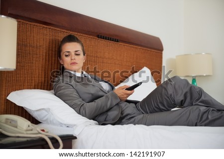 Concerned business woman laying on bed in hotel room and waiting phone call