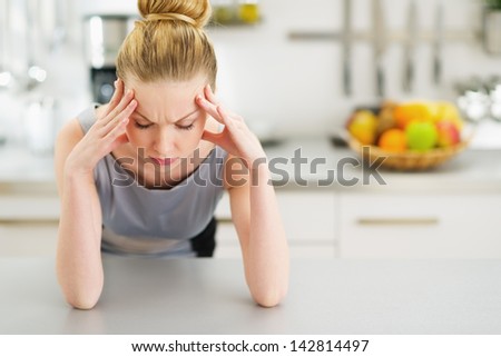 Portrait of stressed young housewife in modern kitchen