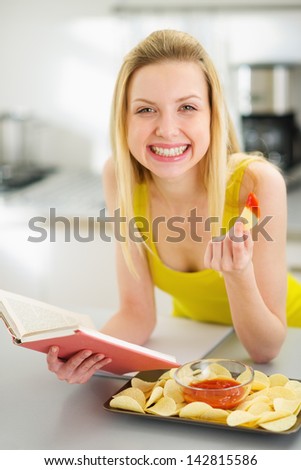 Teenage girl reading book and eating chips