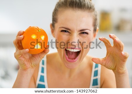 Young woman scaring with orange with hallowing face