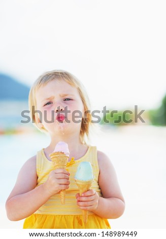 Happy baby enjoying two ice cream