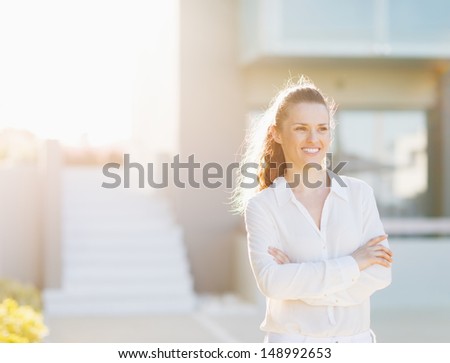 Portrait of happy young woman standing in front of house building
