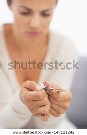 Closeup on pills pack in hand of ill young woman laying on sofa