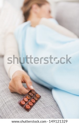 Closeup on pills pack in hand of ill young woman