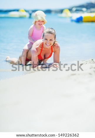Happy mother and baby playing on sea shore