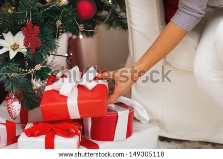 Closeup on woman putting christmas present box under christmas tree
