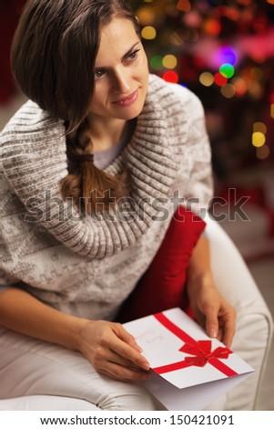 Portrait of young woman with postcard in front of christmas lights