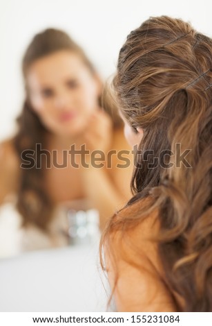 Closeup on woman looking in mirror in bathroom