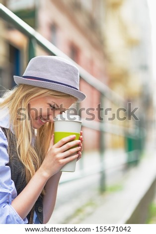 Smiling Hipster Girl With Cup Of Hot Beverage On City Street