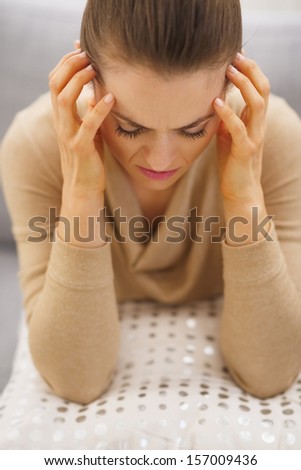 Portrait of stressed young housewife sitting on divan