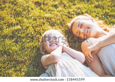 Smiling mother and baby laying on meadow