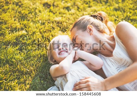 Happy mother and baby laying on meadow