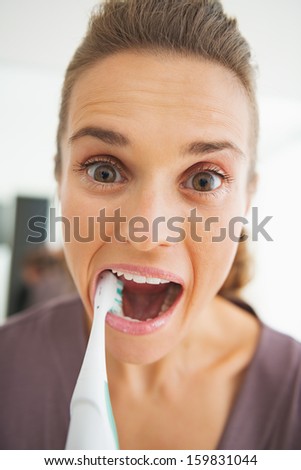 Funny portrait of young woman intensively brushing teeth